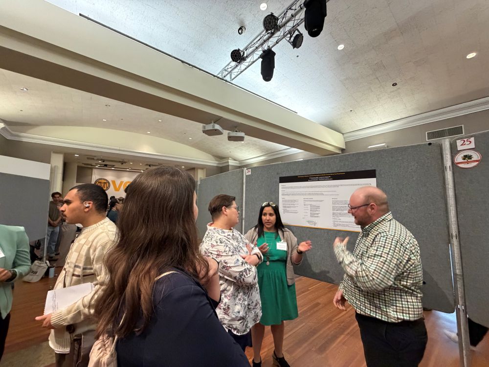 Two people presenting their research to others at grad symposium 2026